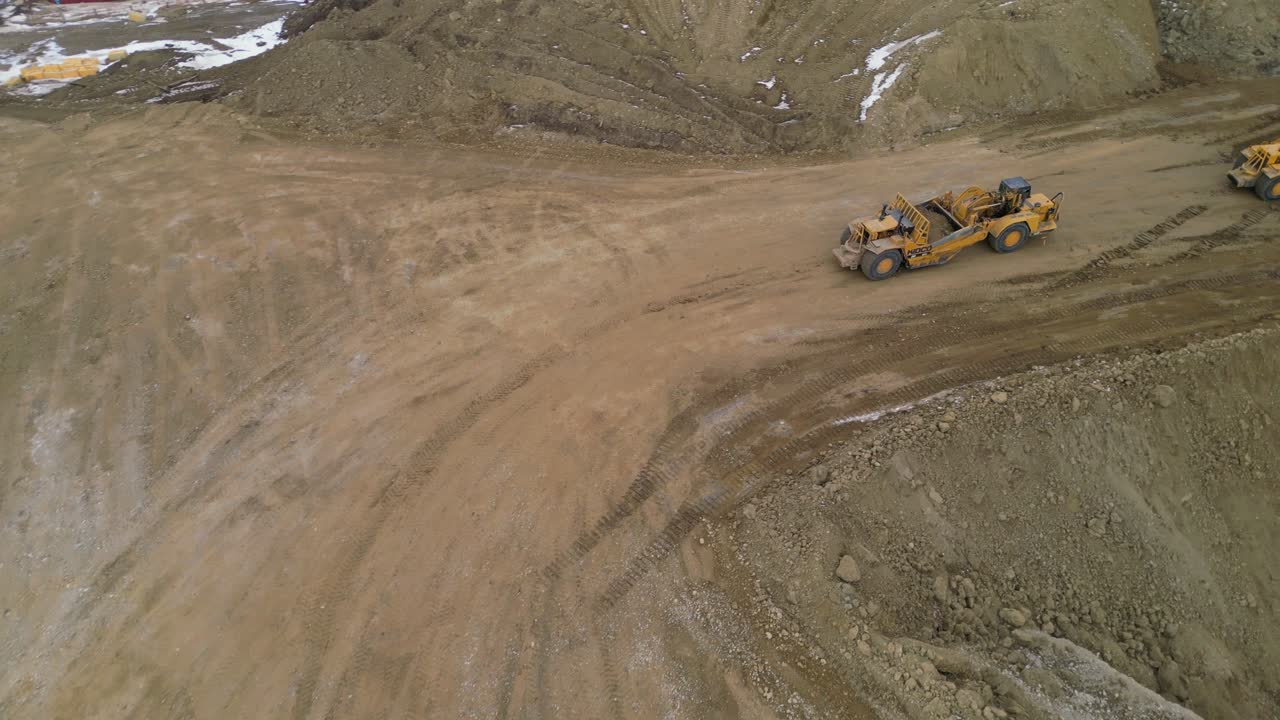 los raspadores de tractores de ruedas trabajan en un sitio de construcción para nivelar y calificar un área para un nuevo desarrollo de viviendas visto desde un punto de vista aéreo de drones