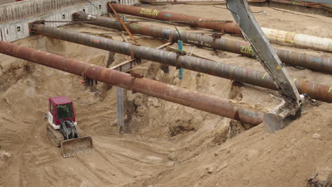 excavation pit with pipes and excavator at a construction site