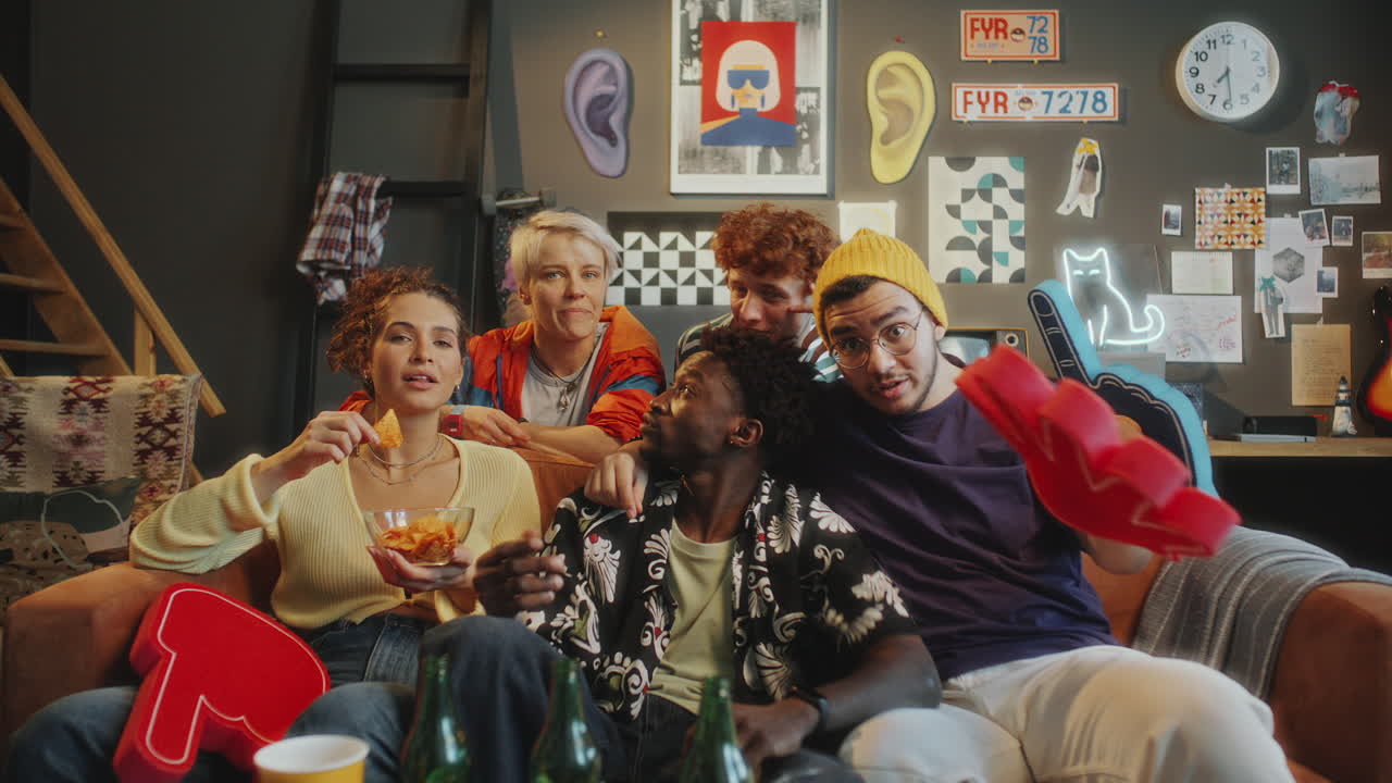 Friends Enjoying Snacks and Laughing at TV Show on Couch in Living Room