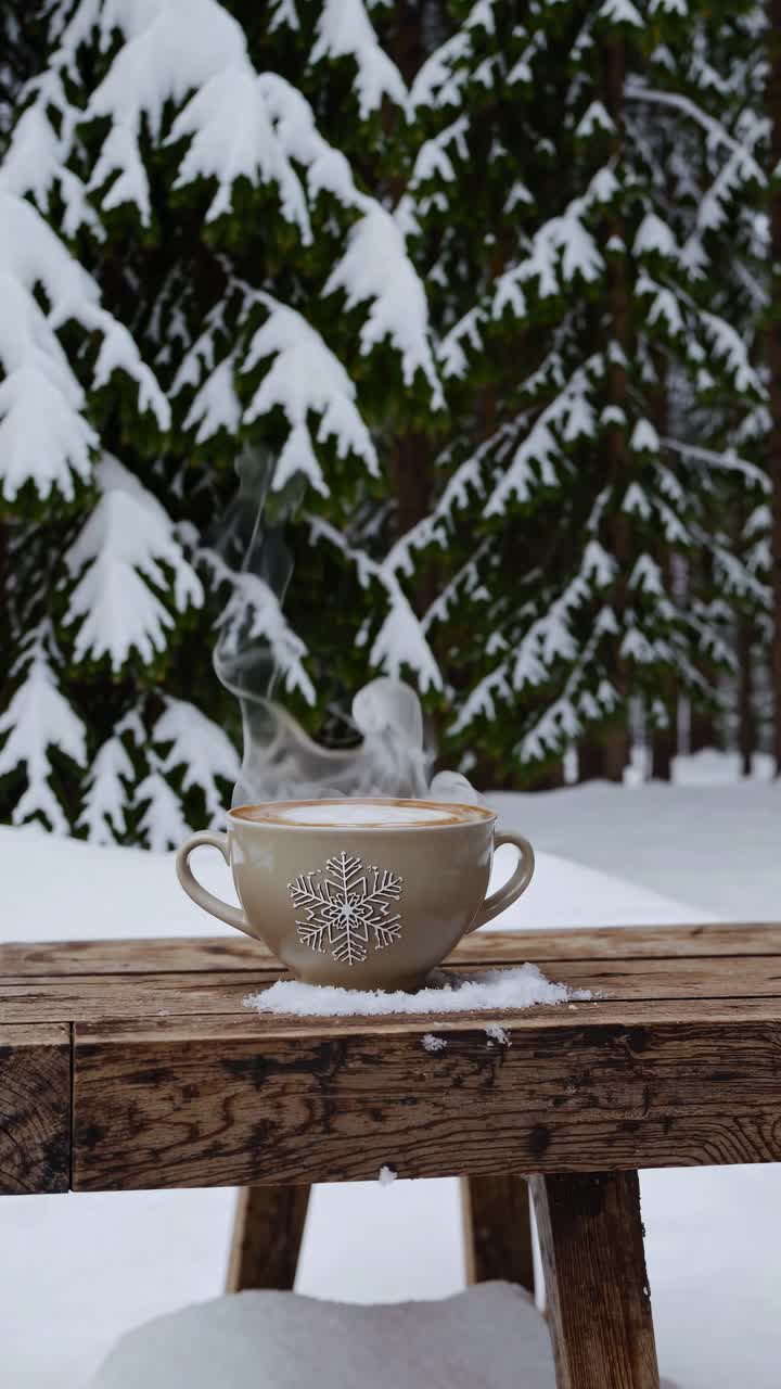 A steaming cup on a wooden table in a snowy forest, captured from a low angle
