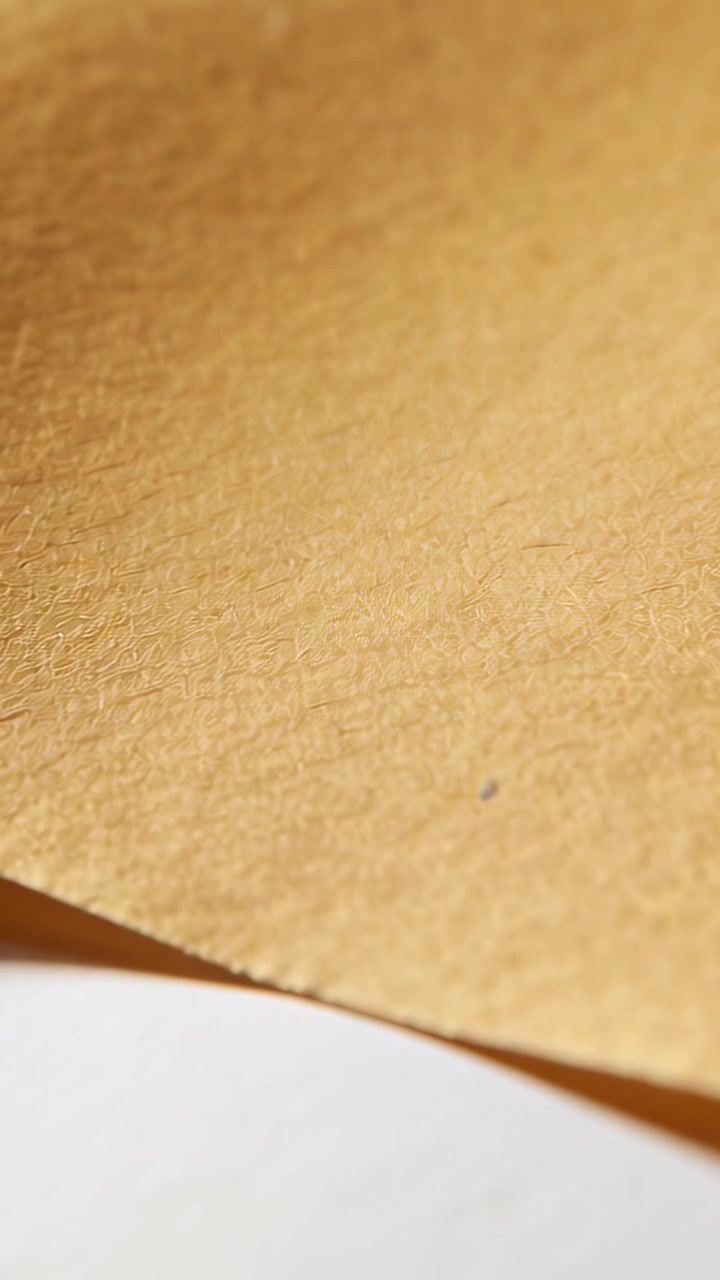 Vertical video: Settling camera capturing brown kraft paper on table, with white curve for texture