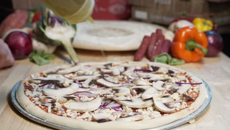 Close-up-of-hands-of-a-skilled-chef-sprinkled-olive-oil-on-pizza-dough-with-fresh-mushrooms,-mozzarella-cheese-and-juicy-red-sauce