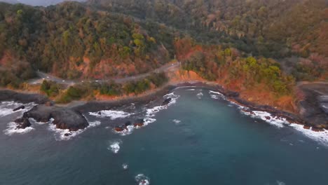 aerial cinematic shot approaching a traffic road parallel to the beach coast at dusk, costa rica