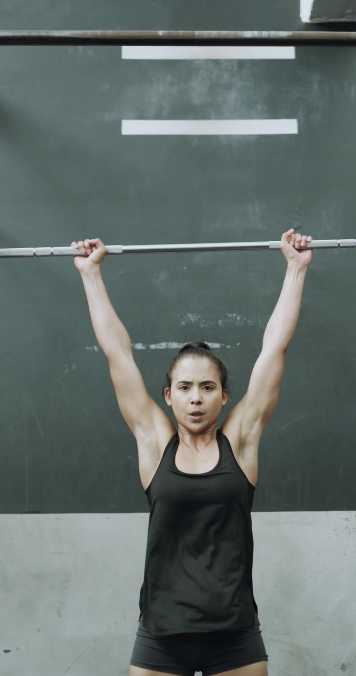 Donna in Forma che Esegue un Overhead Press con Bilanciere in Palestra