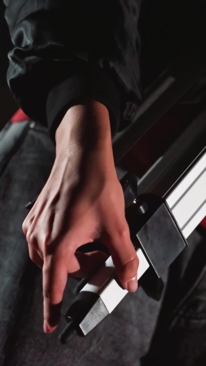 Mano con anillo ajusta componentes metálicos y presiona el piano. Los detalles finos incluyen un anillo en el dedo índice. La composición fuertemente encuadrada se centra en acciones detalladas