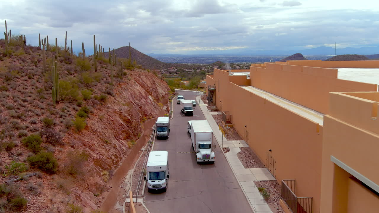 Ripresa con drone di camion che arrivano dietro un hotel o un grande edificio.