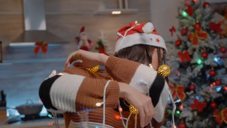 Woman-with-santa-hat-tangled-in-garland-of-lights