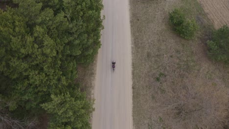 a following aerial drone shot of a gravel cyclist riding down a gravel road in the durham region