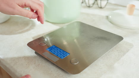 close up of hand activating electric stove and gently touching metal surface to check temperature, modern kitchen counter with digital scale and kitchen tools