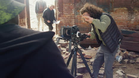 cameraman setting up a camera in a ruined building while another coworkers planning the recording