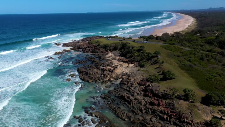 Ripresa con drone che parte da un affioramento roccioso costiero e si apre a un campo largo a Cabarita Beach, Australia