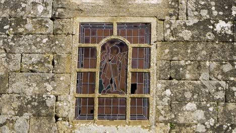 stained glass window showing wanderer in humble clothes set in stone wall facade