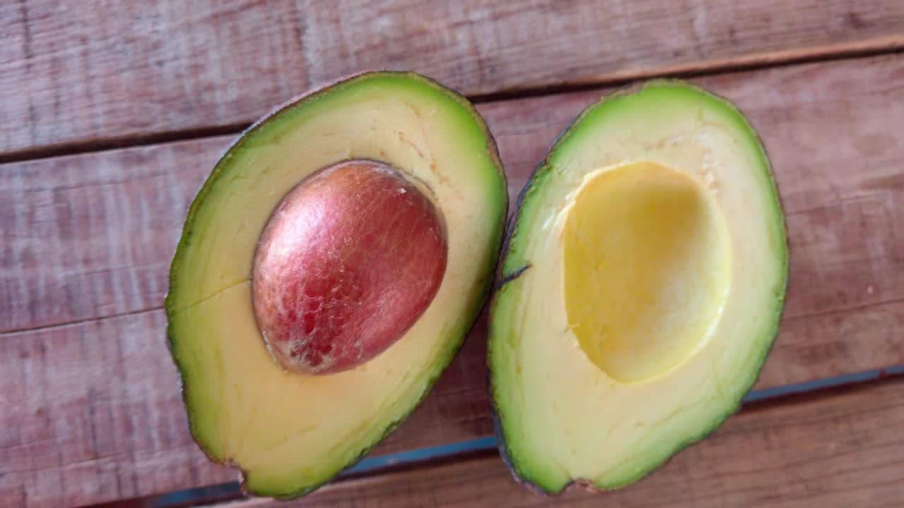 Top down shot of avocado slice on a wooden table, handheld shot