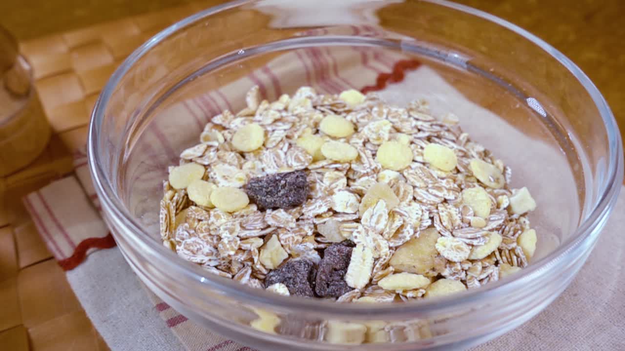 muesli de cereales de grano entero en un tazón para un delicioso desayuno matutino con leche. cámara lenta con toma de seguimiento de rotación.