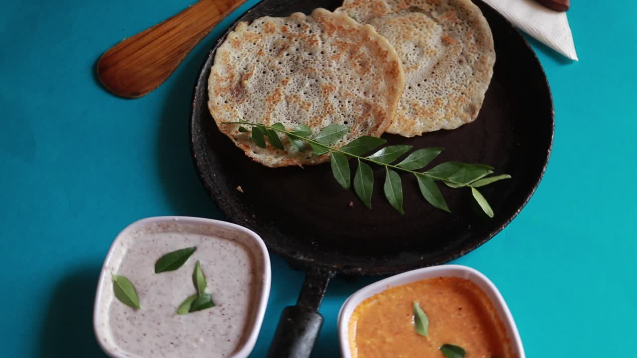 conjunto giratorio de comida del sur de la india dosa con curry y chutney sobre fondo azul