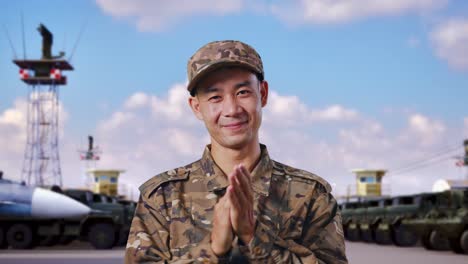 close up of asian man soldier smiling and clapping his hands while standing at military camp