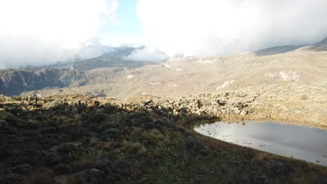 Pull-back-aerial-reveal-shot-over-mountains-in-South-America-with-sun-and-cloud