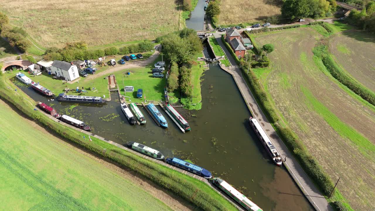 Cinematic drone reveal of lock gate operation and leisure barges cruising past reedbeds on a sunny fall day