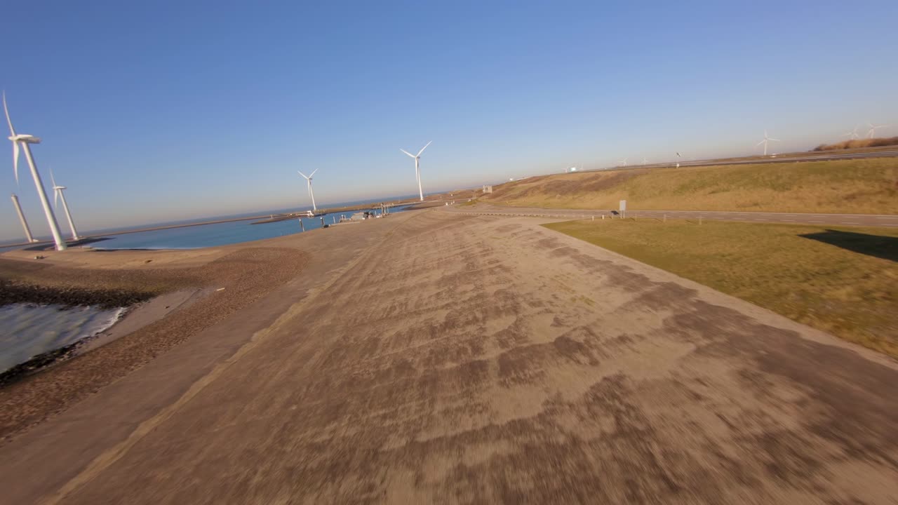 Soaring above a dyke towards large windturbines on Neeltje Jans