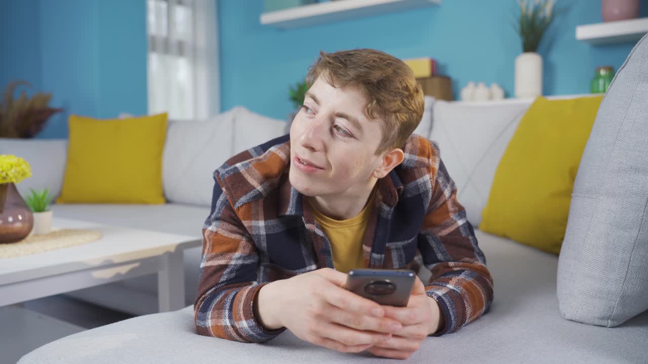 행복한 젊은이가 집에 누워서 전화로 얘기하고 있습니다.