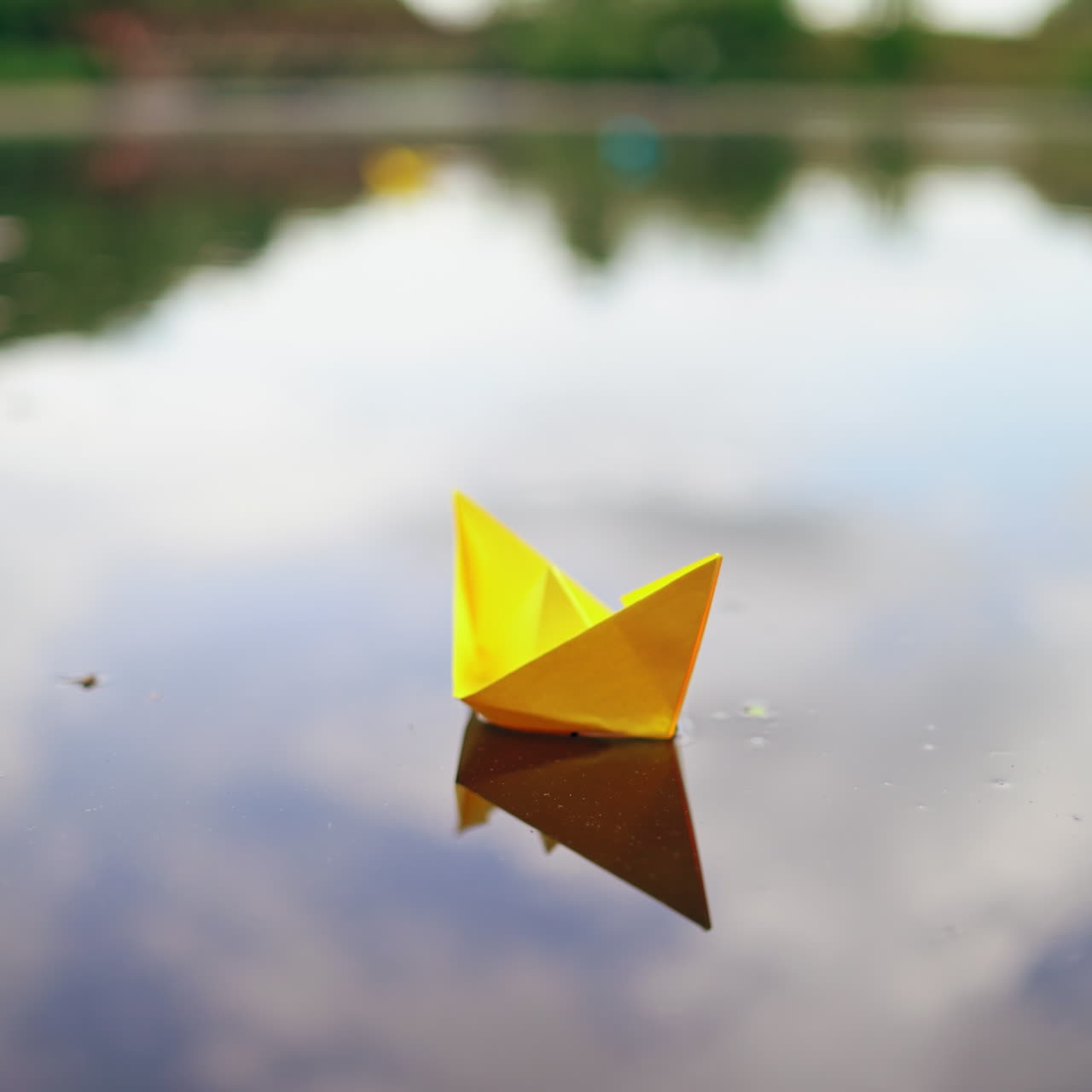 Woman's hand launches paper boat on the water. Paper boat sails along the river.