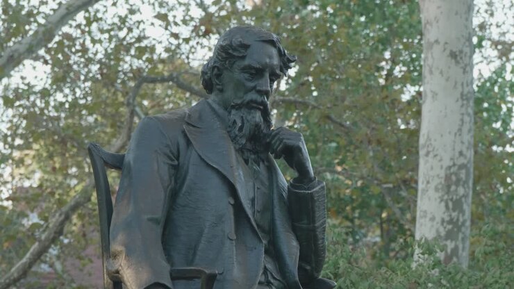 Bronzestatue af en siddende mand i en park
