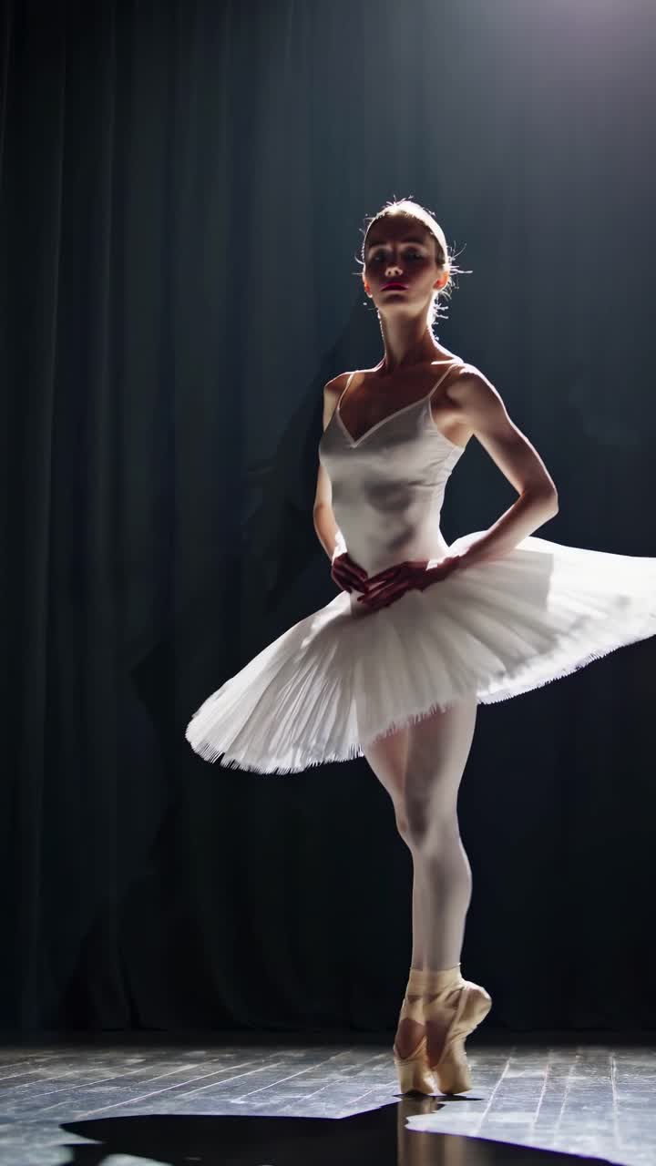Elegante ballerina in tutù bianco catturata sotto un riflettore drammatico da un'angolazione bassa.