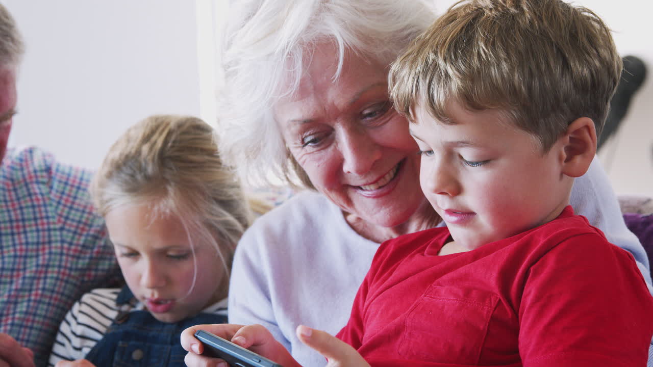 nonni che giocano ai videogiochi con i nipoti sul cellulare a casa