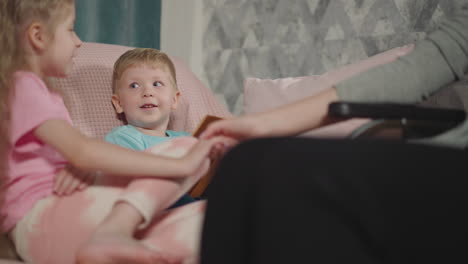 Little-boy-examines-book-while-mom-and-sister-holding-hands