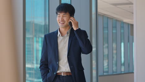 asian-businessman-using-smartphone-chatting-to-client-financial-advisor-negotiating-business-deal-corporate-sales-executive-sharing-expert-advice-having-phone-call-in-office-looking-out-window