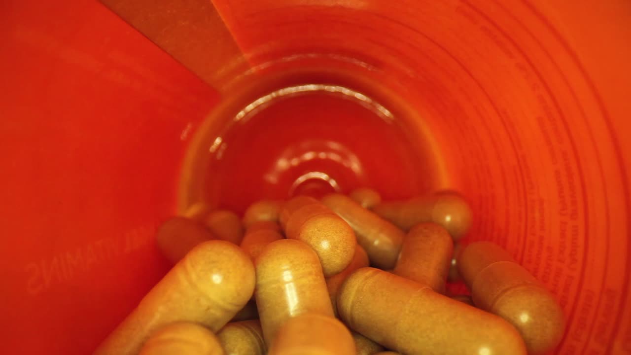 주황색 보충제 약병의 전체 길이의 절반을 빼내어 병 뚜껑을 드러냅니다.