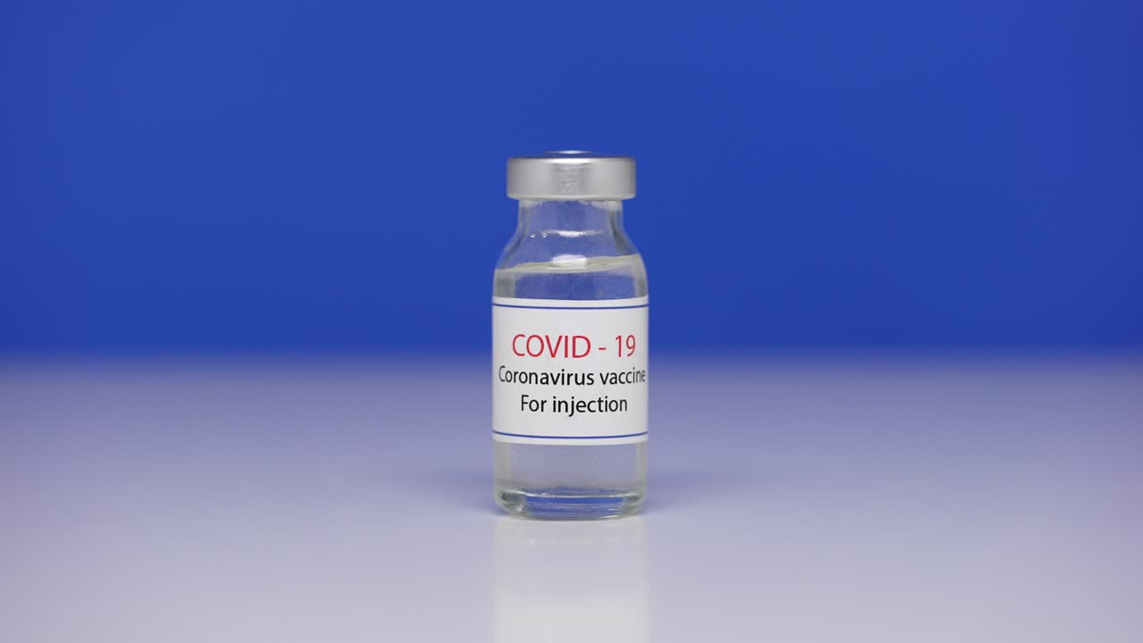 cerrar el vial con la vacuna contra el coronavirus covid-19. botella de vacuna against sars-cov-2 virus en la mesa de laboratorio de fondo. medicamentos contra la pandemia de ncov. pantalla azul, llave de croma. cerrar. lento