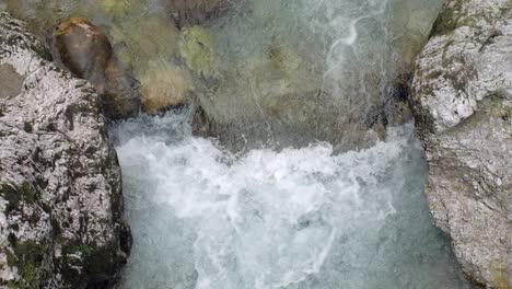 Wild-clear-mountain-river-rapid-foaming-between-two-rocks,-zoom-in