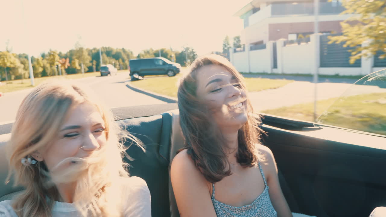 dos amigos divirtiéndose en un coche convertible