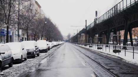 calle grande al lado del paso elevado con autos cubiertos de nieve estacionados al lado de la carretera