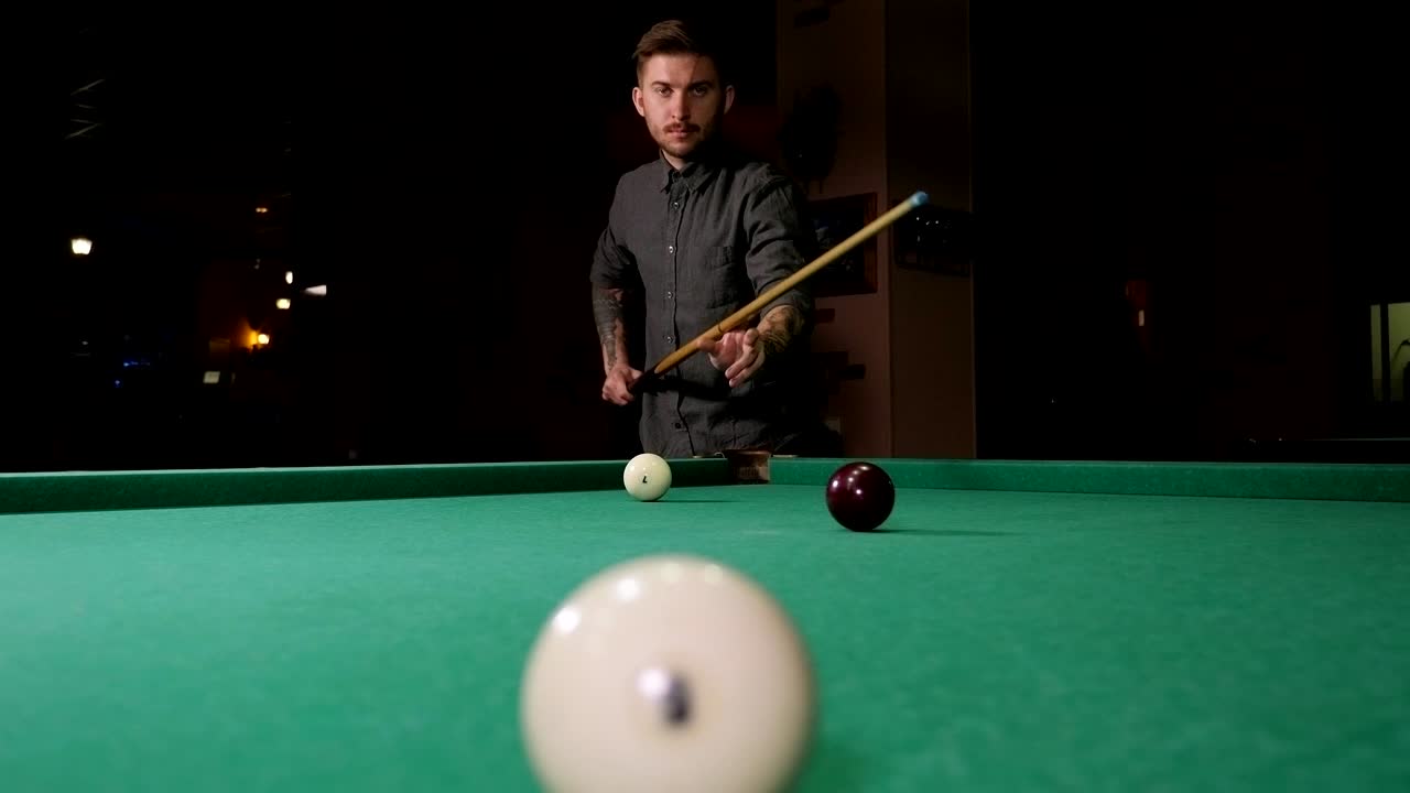Jonge succesvolle knappe man speelt Russisch biljart in een bar met vrienden.