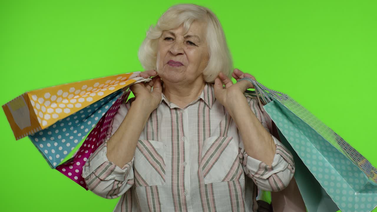 상급 할머니가 쇼핑 가방을 올리고, 축하하고, 구매에 만족하고, 할인합니다.