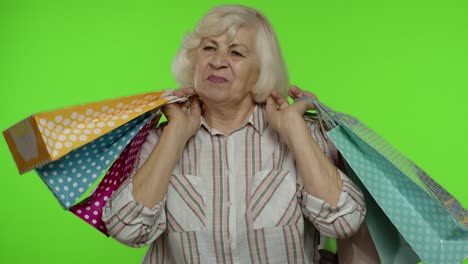 abuela mayor levantando bolsas de compras, celebrando, satisfecha con la compra, descuento. llave de croma