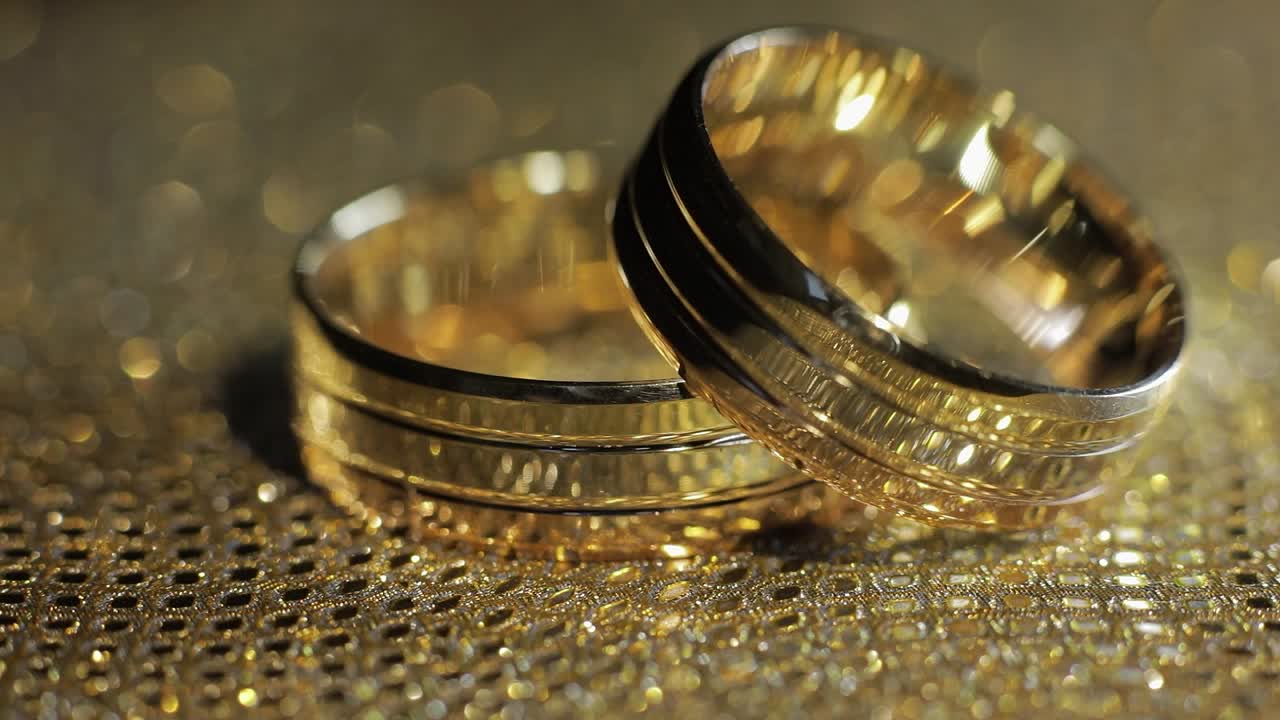 Wedding gold rings lying on shiny glossy surface. Shining with light. Close-up