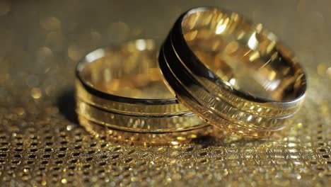 wedding gold rings lying on shiny glossy surface. shining with light. close-up