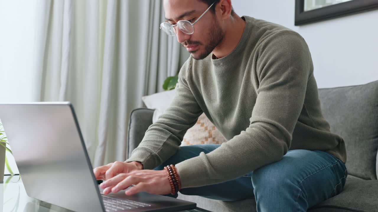 Man, glasses and laptop working on sofa