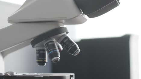 microbiólogo masculino, trabajador médico mira una muestra de sangre a través de un microscopio, hace análisis en el laboratorio. asistente de laboratorio lleva a cabo una investigación histológica de biomateriales utilizando un microscope moderno.