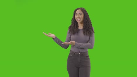 retrato de una mujer que presenta o demuestra un elemento contra una pantalla verde sonriendo a la cámara 2