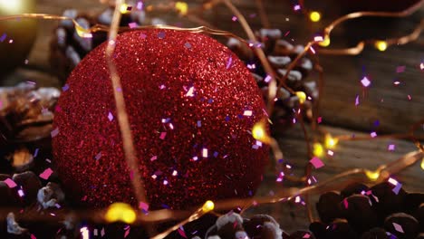 animation of confetti falling over christmas decoration with fairy lights and baubles