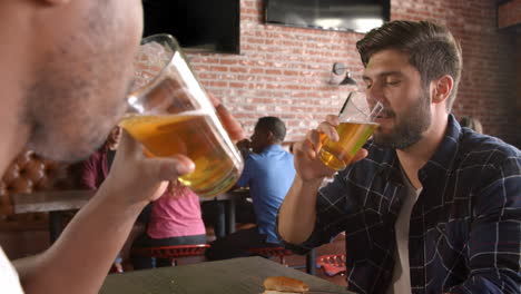 Dos-Amigos-Varones-Comiendo-En-El-Bar-De-Deportes