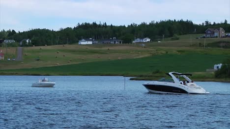 Two-boats-pass-by-each-other-on-the-Bouctouche-River-near-the-village-of-Sainte-Marie-de-Kent-in-New-Brunswick,-Canada