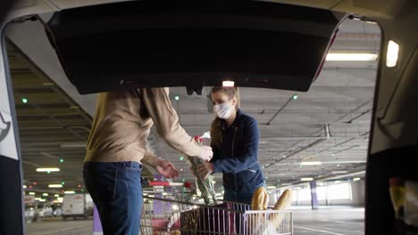 front view of couple packing bags in a car trunk