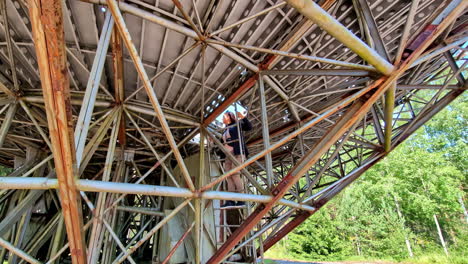 woman exploring the ruins of a giant soviet-era radio telescope