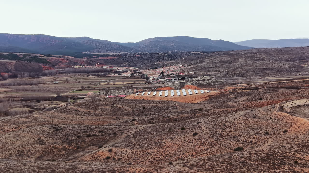 Painéis solares são instalados em uma colina perto de uma pequena aldeia no campo durante um dia nublado no início da primavera.