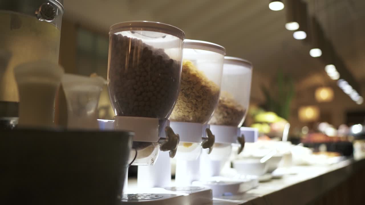 disparo general lento de contenedores de cereales transparentes sobre la mesa blanca en el desayuno del hotel